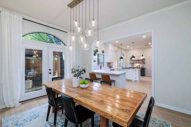 dining room with crown molding, baseboards, french doors, and light wood-style floors