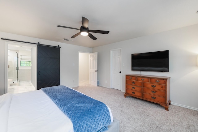 carpeted bedroom featuring visible vents, baseboards, a barn door, a ceiling fan, and ensuite bath