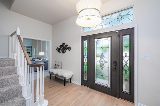 foyer with baseboards, stairs, and wood finished floors