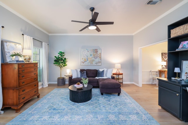 sitting room featuring ceiling fan, baseboards, light wood-type flooring, visible vents, and ornamental molding