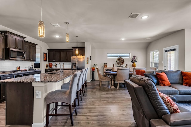 621 Hazeltine Rd, Red Oak, TX 75154 - kitchen featuring open floor plan, appliances with stainless steel finishes, a sink, hardwood / wood-style flooring, and dark stone counters