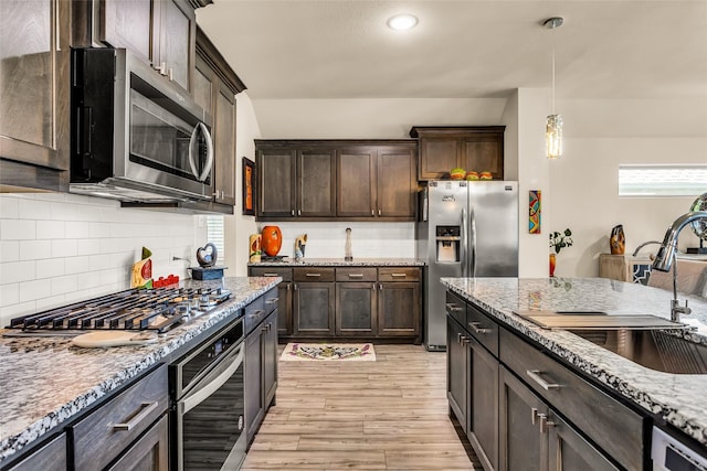 621 Hazeltine Rd, Red Oak, TX 75154 - kitchen with light stone countertops, appliances with stainless steel finishes, dark brown cabinetry, a sink, and light wood-type flooring