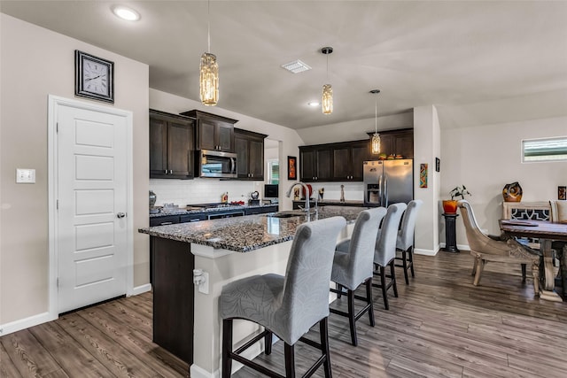 621 Hazeltine Rd, Red Oak, TX 75154 - kitchen featuring appliances with stainless steel finishes, a sink, dark wood-style floors, dark stone counters, and a breakfast bar