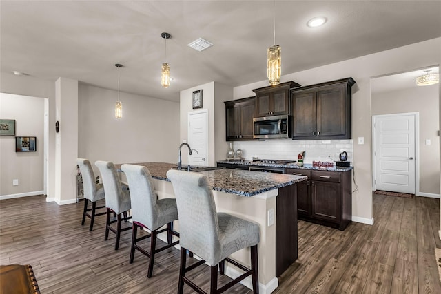 621 Hazeltine Rd, Red Oak, TX 75154 - kitchen featuring stainless steel microwave, dark wood-type flooring, a sink, dark stone countertops, and recessed lighting