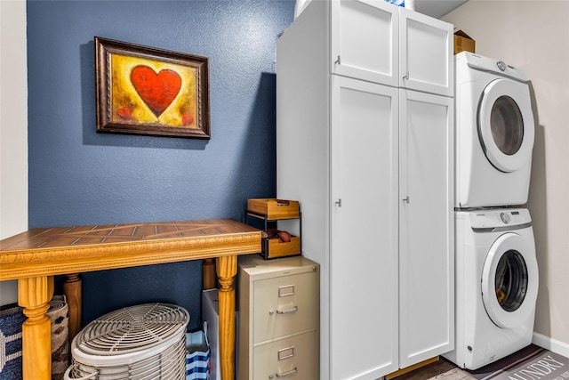 621 Hazeltine Rd, Red Oak, TX 75154 - laundry area with cabinet space, stacked washer and clothes dryer, a textured wall, and baseboards