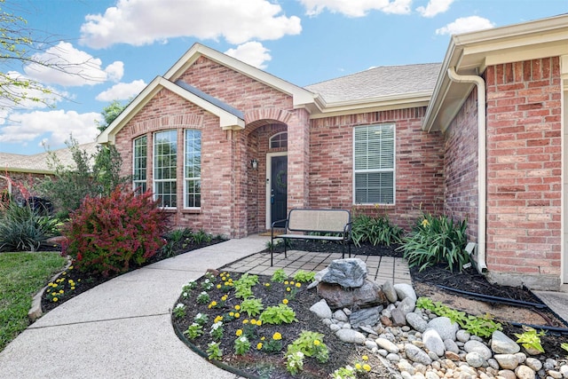 view of front of home with brick siding, driveway, an attached garage, a front lawn, and roof with shingles