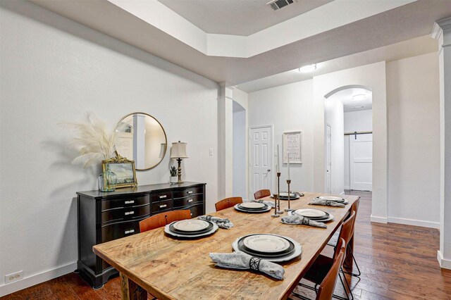living area featuring hardwood / wood-style floors, baseboards, and a tray ceiling