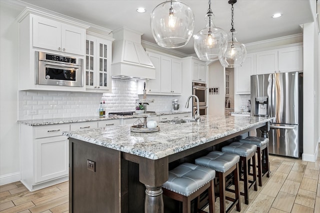 kitchen featuring white cabinets, wood finish floors, appliances with stainless steel finishes, and a sink