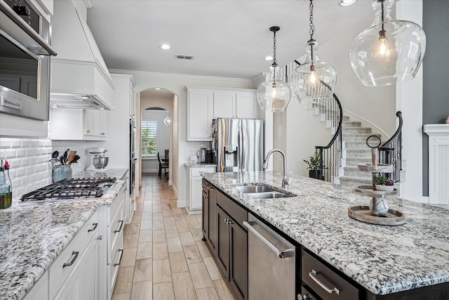kitchen with visible vents, arched walkways, a sink, white cabinets, and stainless steel appliances