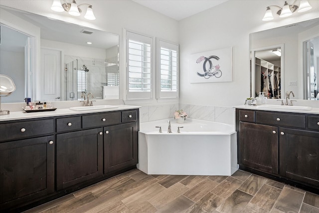 full bathroom featuring a sink, two vanities, a shower stall, visible vents, and a bath