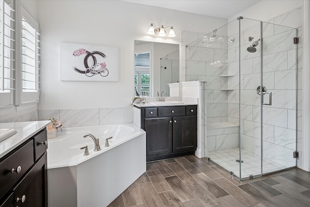full bathroom featuring a garden tub, wood finished floors, two vanities, a sink, and a stall shower