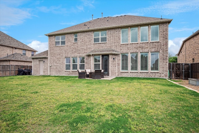 back of house with a fenced backyard, a patio, a yard, and brick siding