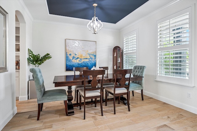 dining area featuring baseboards, ornamental molding, wood finished floors, and a chandelier