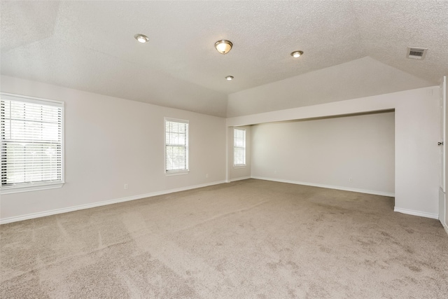 empty room with visible vents, baseboards, carpet floors, and vaulted ceiling