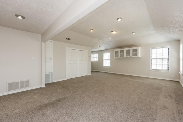 interior space featuring carpet flooring, a textured ceiling, and visible vents