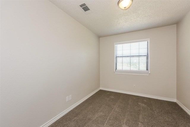 unfurnished room with baseboards, dark carpet, a textured ceiling, and visible vents
