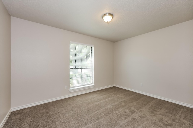spare room featuring baseboards and dark colored carpet