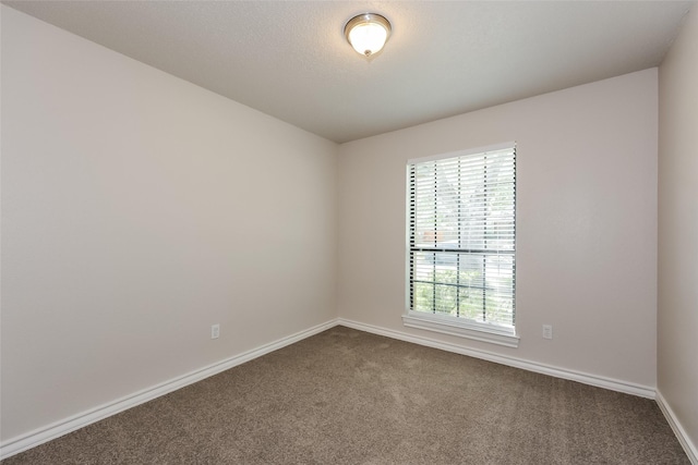 empty room featuring baseboards and dark carpet