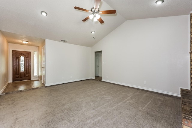 unfurnished living room with ceiling fan, visible vents, vaulted ceiling, baseboards, and carpet