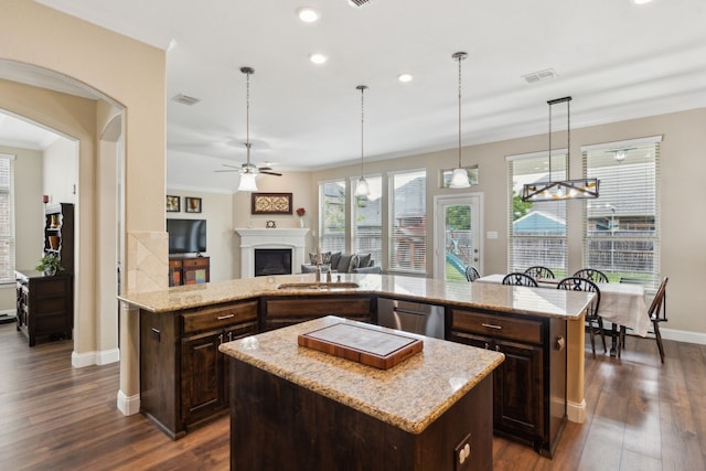 kitchen with a center island, baseboards, a fireplace, and dark brown cabinetry