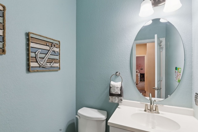 half bath featuring vanity and toilet