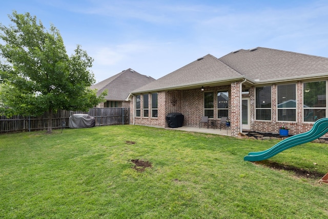 back of house with a lawn, brick siding, fence, and a shingled roof