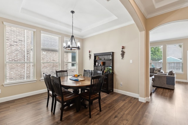 dining area featuring a notable chandelier, arched walkways, baseboards, dark wood-type flooring, and a tray ceiling