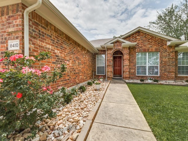 8410 Victory St, Rowlett, TX 75089 - view of exterior entry featuring a lawn and brick siding