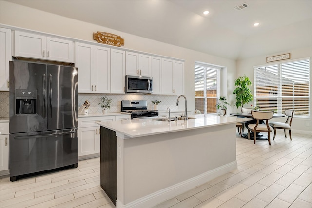 kitchen with visible vents, light countertops, a sink, appliances with stainless steel finishes, and backsplash