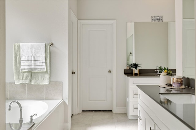 bathroom with vanity, tile patterned floors, baseboards, and a bath