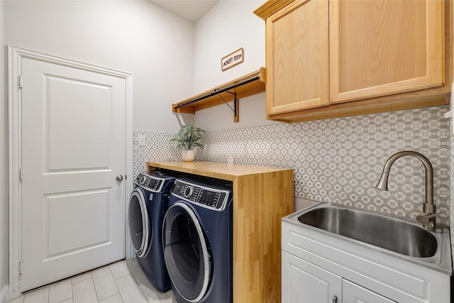 washroom with a sink, light tile patterned flooring, cabinet space, and washing machine and clothes dryer