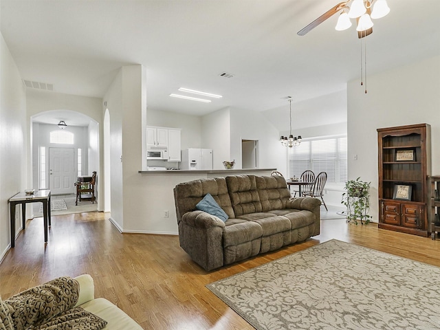 living room with arched walkways, visible vents, and wood finished floors