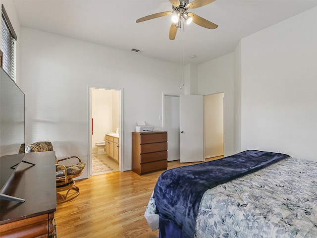 bedroom featuring a ceiling fan, visible vents, light wood finished floors, and ensuite bath