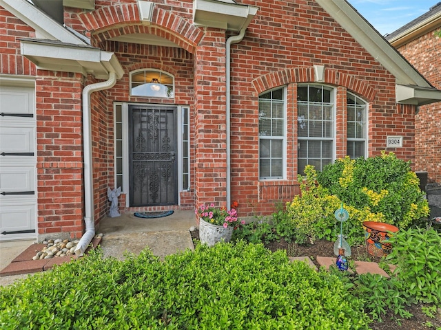 entrance to property featuring brick siding and an attached garage