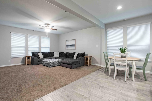 living area featuring baseboards, a ceiling fan, and light wood-type flooring