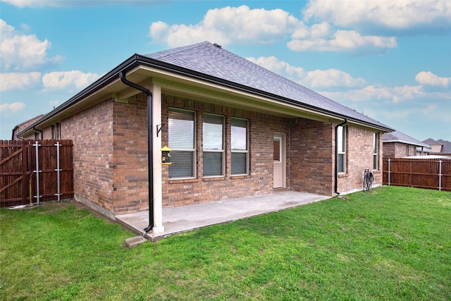 rear view of house with a yard, a patio, brick siding, and a fenced backyard