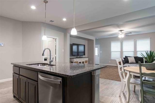 kitchen featuring a sink, dishwasher, dark stone counters, baseboards, and open floor plan