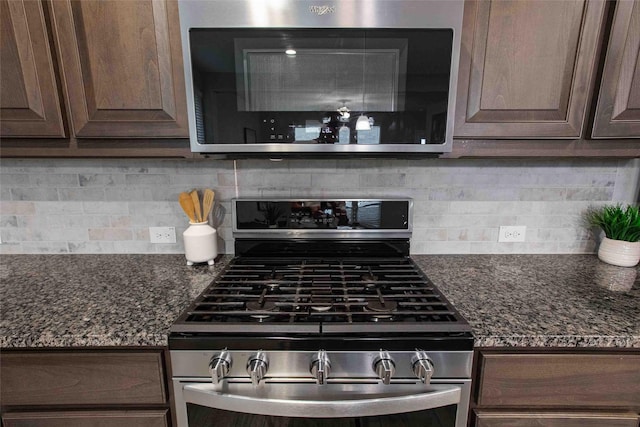 kitchen with dark stone counters, appliances with stainless steel finishes, dark brown cabinetry, and tasteful backsplash