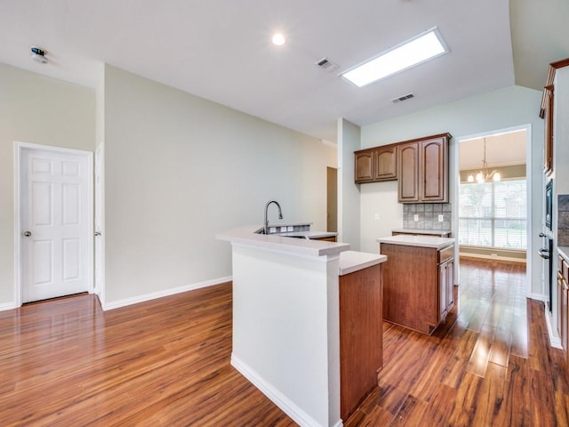 kitchen with an inviting chandelier, visible vents, an island with sink, dark wood-style floors, and a sink