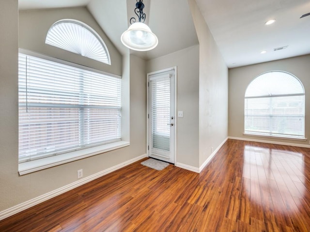 foyer with baseboards, lofted ceiling, wood finished floors, and a healthy amount of sunlight