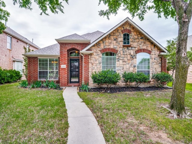 french provincial home with a shingled roof, a front lawn, and stone siding