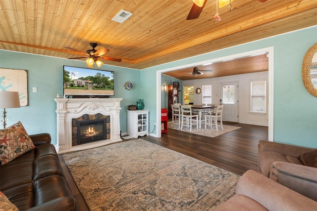 living area with a ceiling fan, visible vents, wood finished floors, wooden ceiling, and a glass covered fireplace