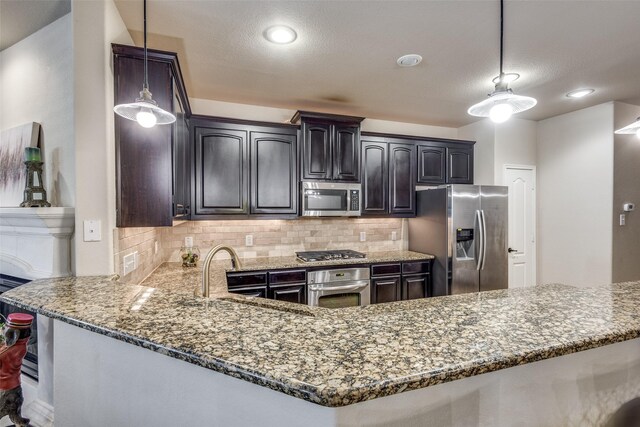 kitchen featuring light stone counters, a sink, stainless steel appliances, decorative backsplash, and pendant lighting