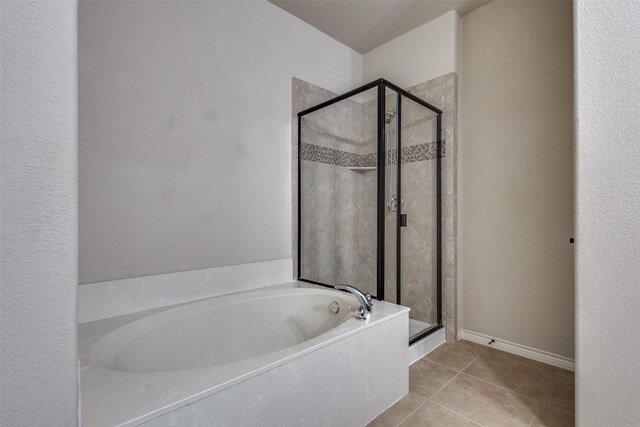 bathroom with tile patterned flooring, a stall shower, baseboards, and a bath