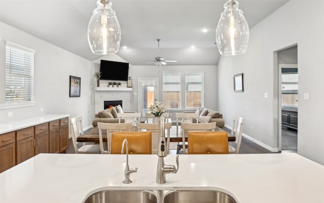 kitchen with vaulted ceiling, a ceiling fan, a lit fireplace, and open floor plan