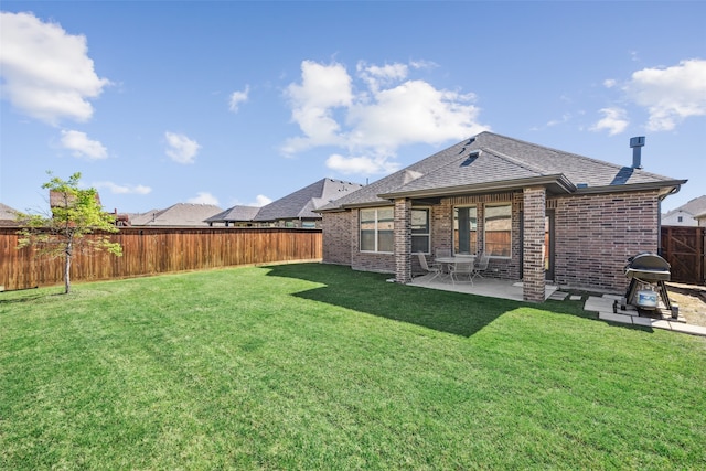 rear view of house featuring a shingled roof, brick siding, a fenced backyard, a patio area, and a lawn