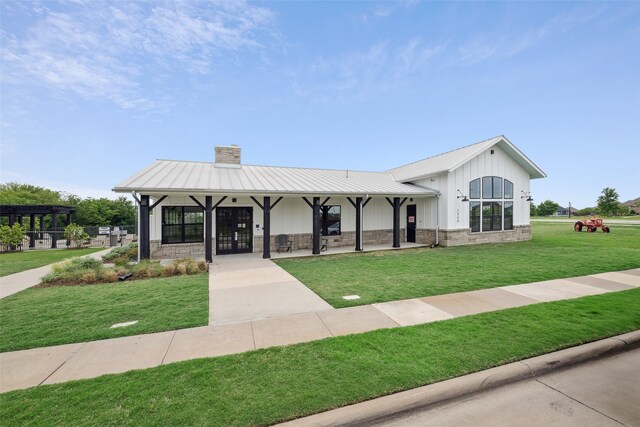view of front of home featuring a standing seam roof, a chimney, a front lawn, and metal roof