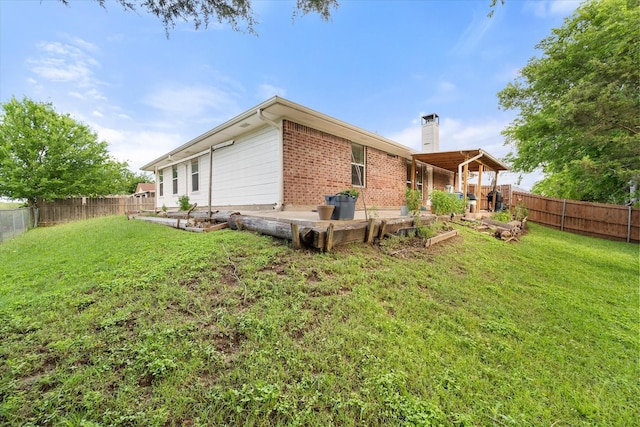 back of house featuring a lawn, a chimney, and a fenced backyard