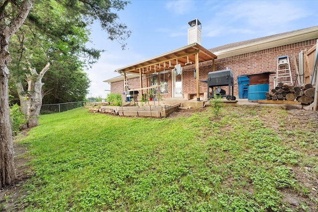 back of property featuring fence, a chimney, a yard, and brick siding