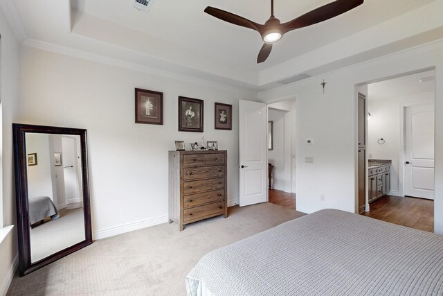 bedroom with visible vents, carpet, a raised ceiling, and ensuite bath